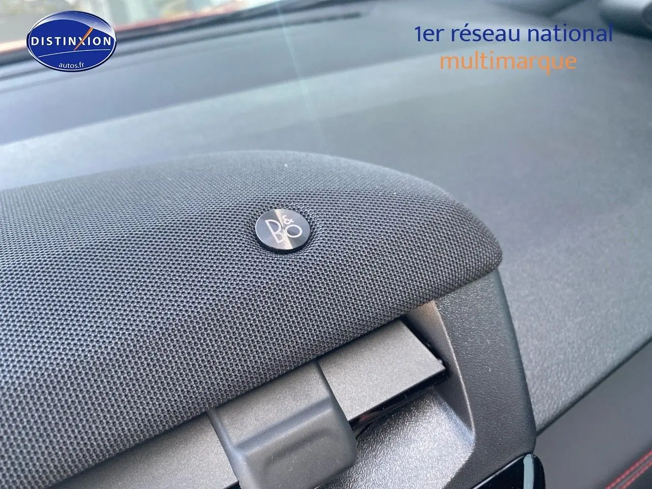 Détail du haut-parleur Bang & Olufsen intégré au tableau de bord du Ford Puma rouge, vue intérieure rapprochée.