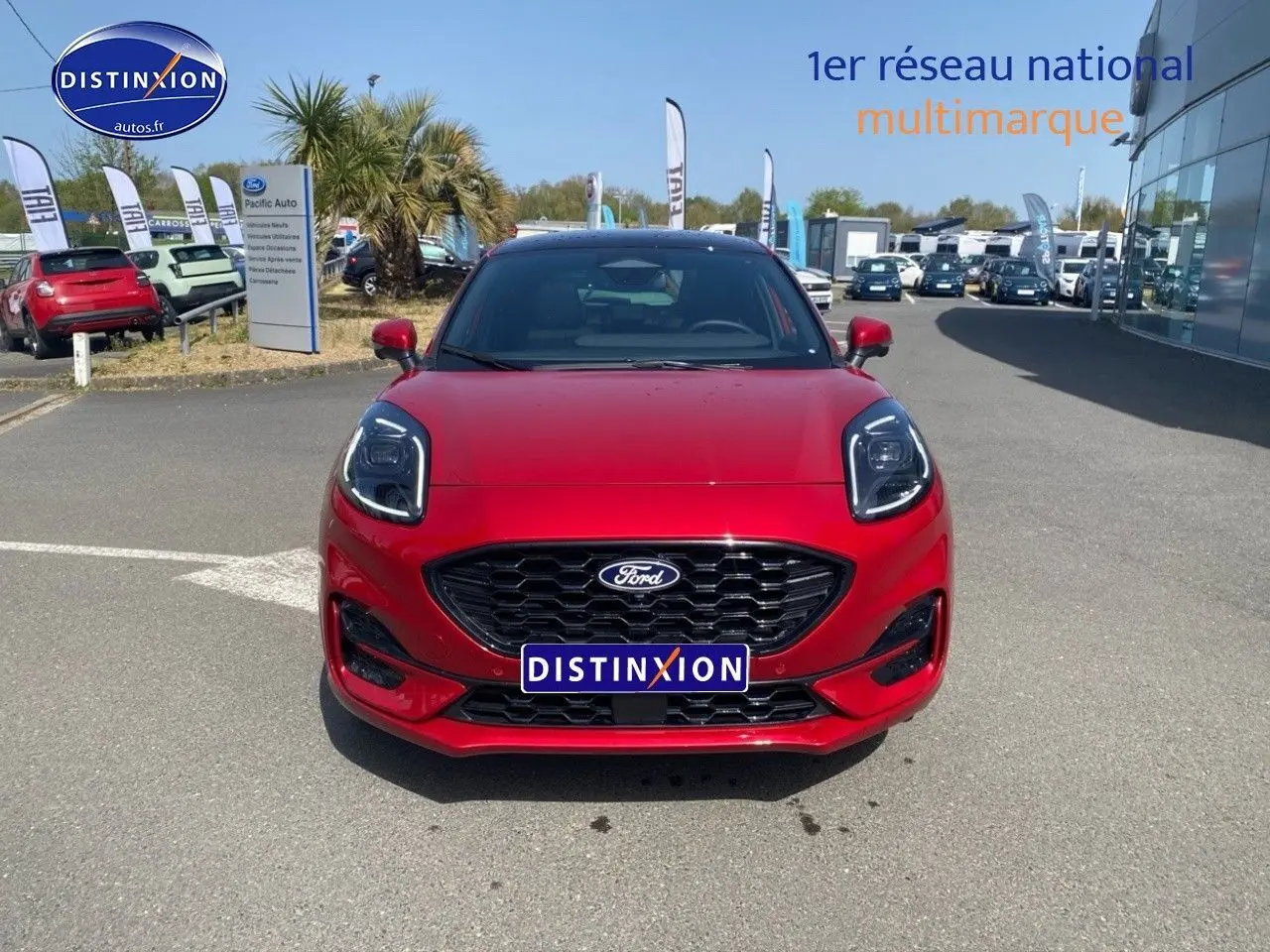 Vue avant d'un Ford Puma rouge métallisé avec calandre noire et phares LED, stationné en extérieur sur parking.