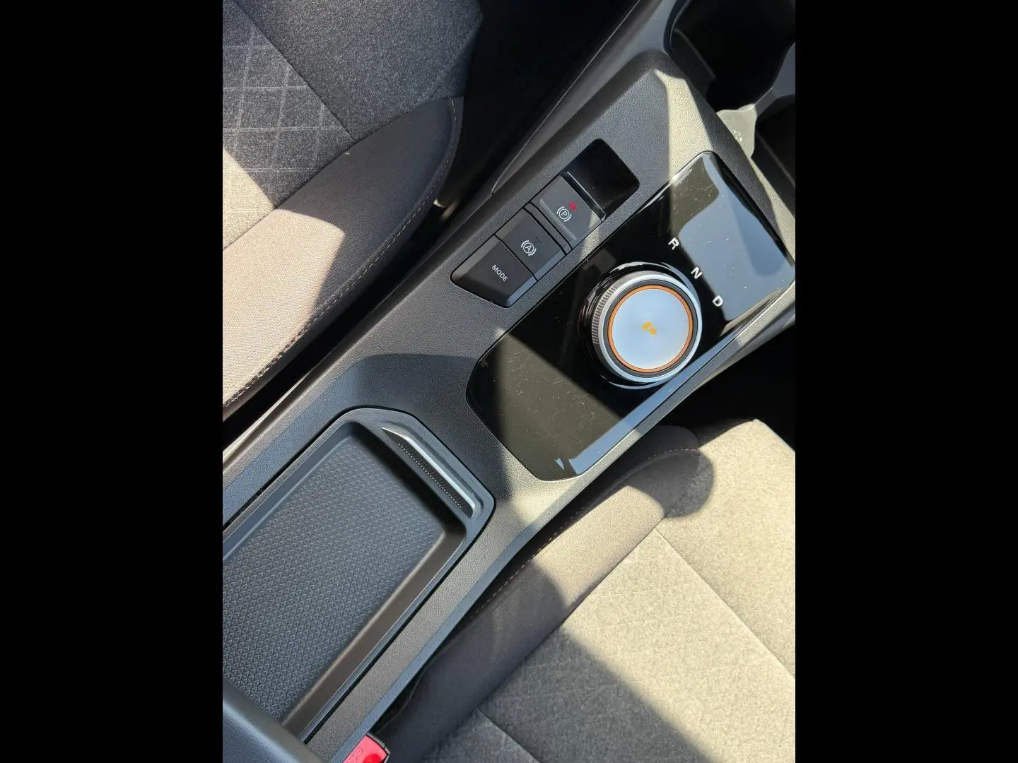 Gros plan sur la console centrale noire avec sélecteur rotatif de boîte auto et tissu gris des sièges du MG3 1.5 Hybrid+ 2025.