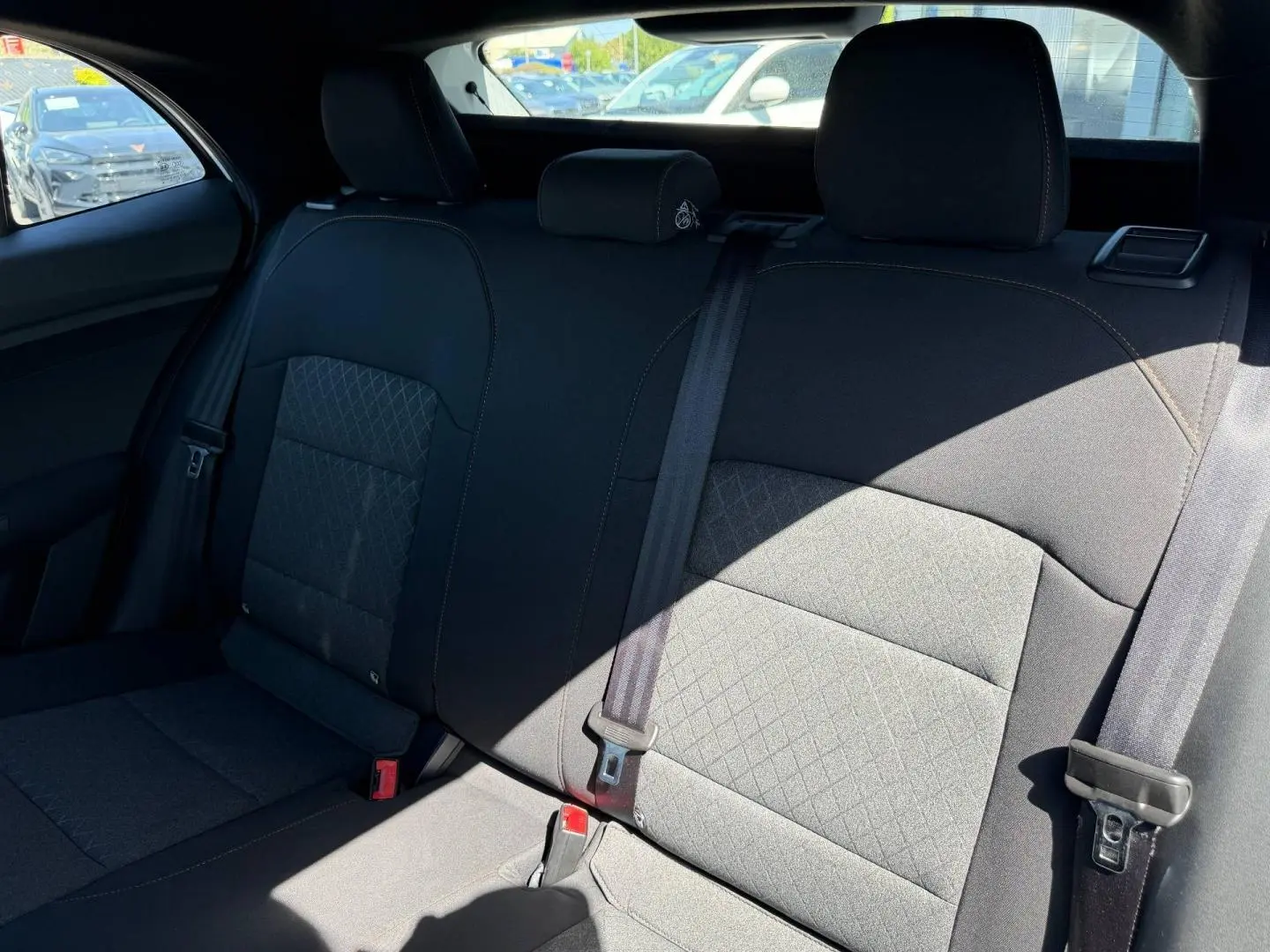 Vue intérieure de la banquette arrière noire en tissu du MG3 1.5 Hybrid+ 195ch Comfort, avec ceintures de sécurité visibles.