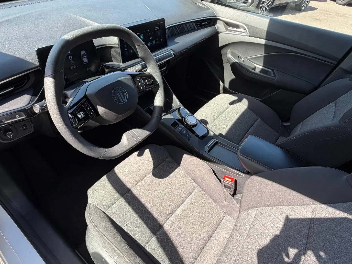 Vue intérieure côté conducteur du MG3 1.5 Hybrid+ 2025 avec sièges tissu gris et volant multifonction noir.