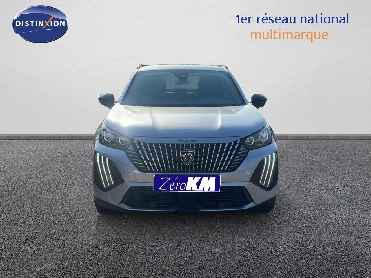 Vue frontale d'un Peugeot 2008 Hybrid 136ch gris Artense métal avec ses phares LED verticaux allumés.