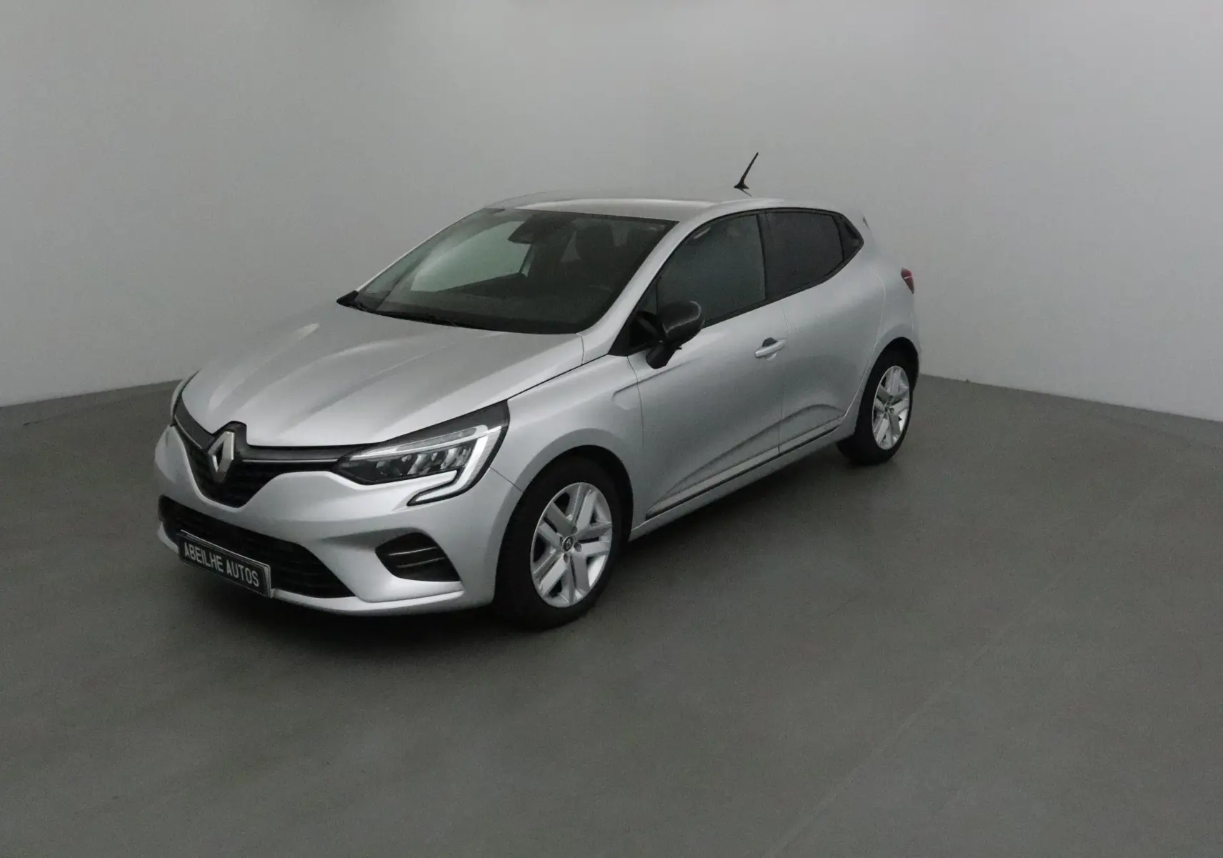 Renault Clio V gris platine vue 3/4 avant droit, avec phares LED et jantes alliage dans un studio neutre.