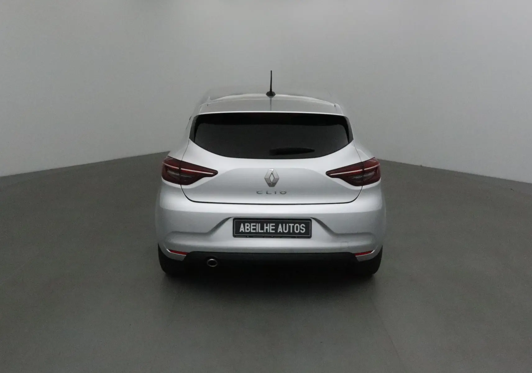 Vue arrière d'une Renault Clio V gris platine 2021 avec feux LED et plaque Abeilhe Autos visible.