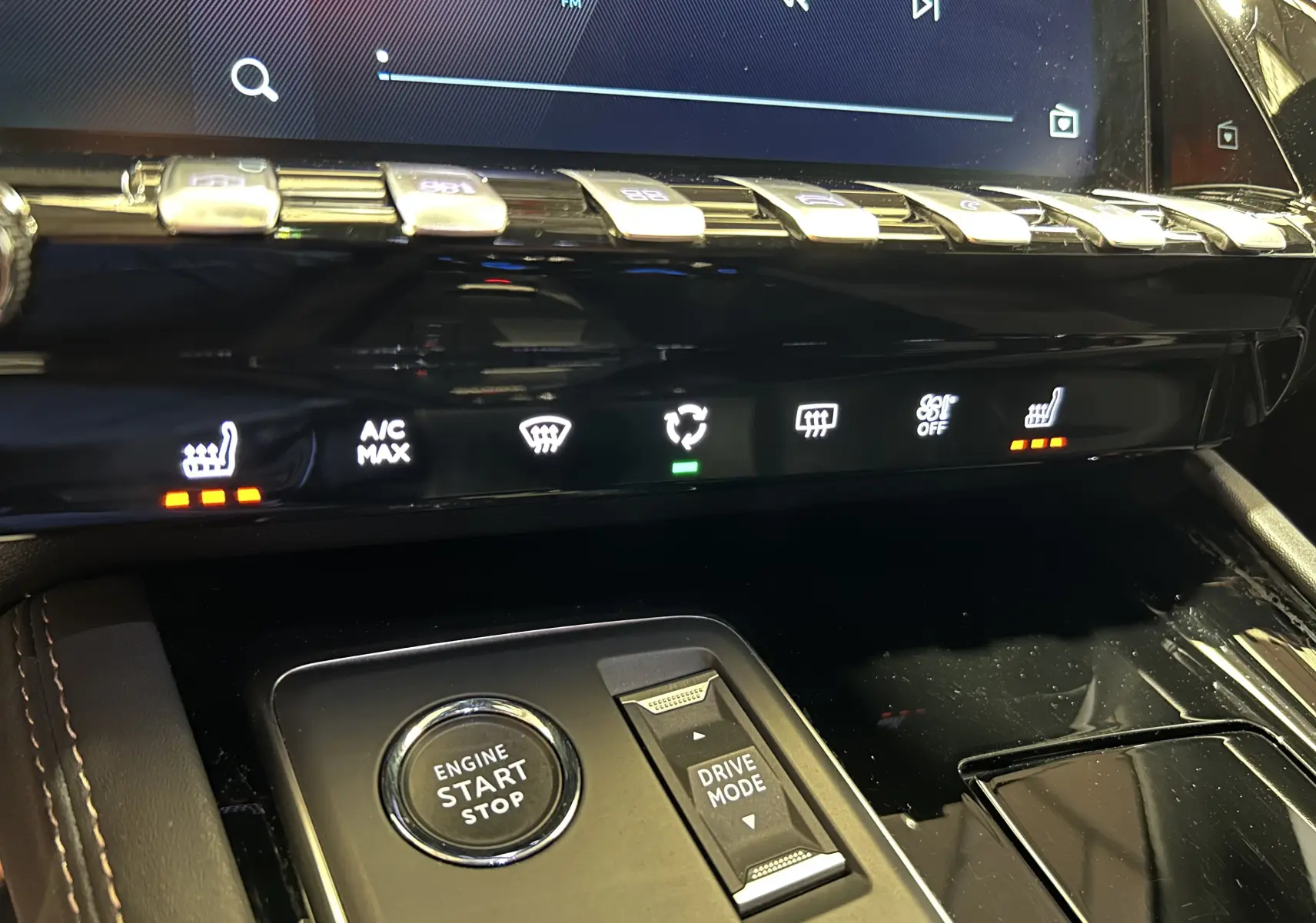 Gros plan sur la console centrale de la Peugeot 508 SW 2024, mettant en valeur les commandes de chauffage des sièges et le bouton start-stop.