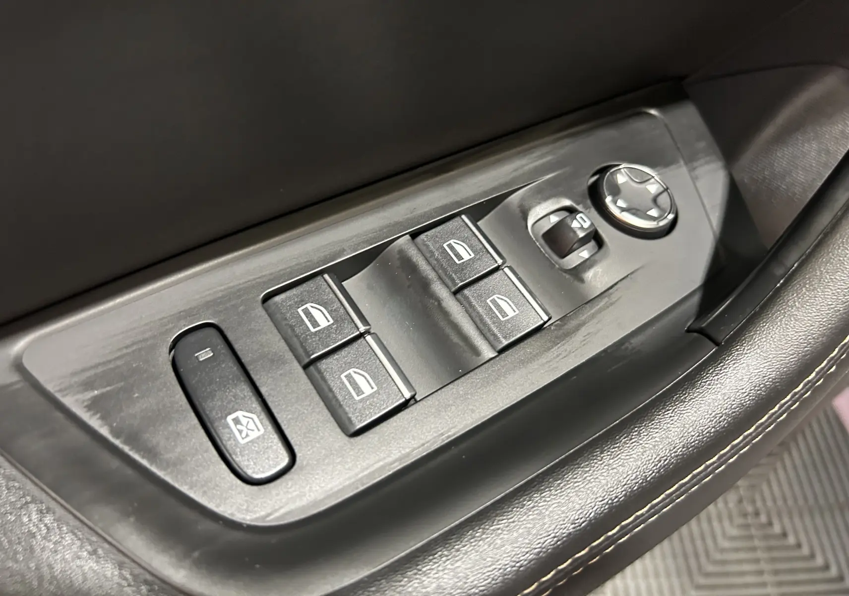 Gros plan sur les commandes de lève-vitres et rétroviseurs côté conducteur du Peugeot 508 SW gris Artense 2024.