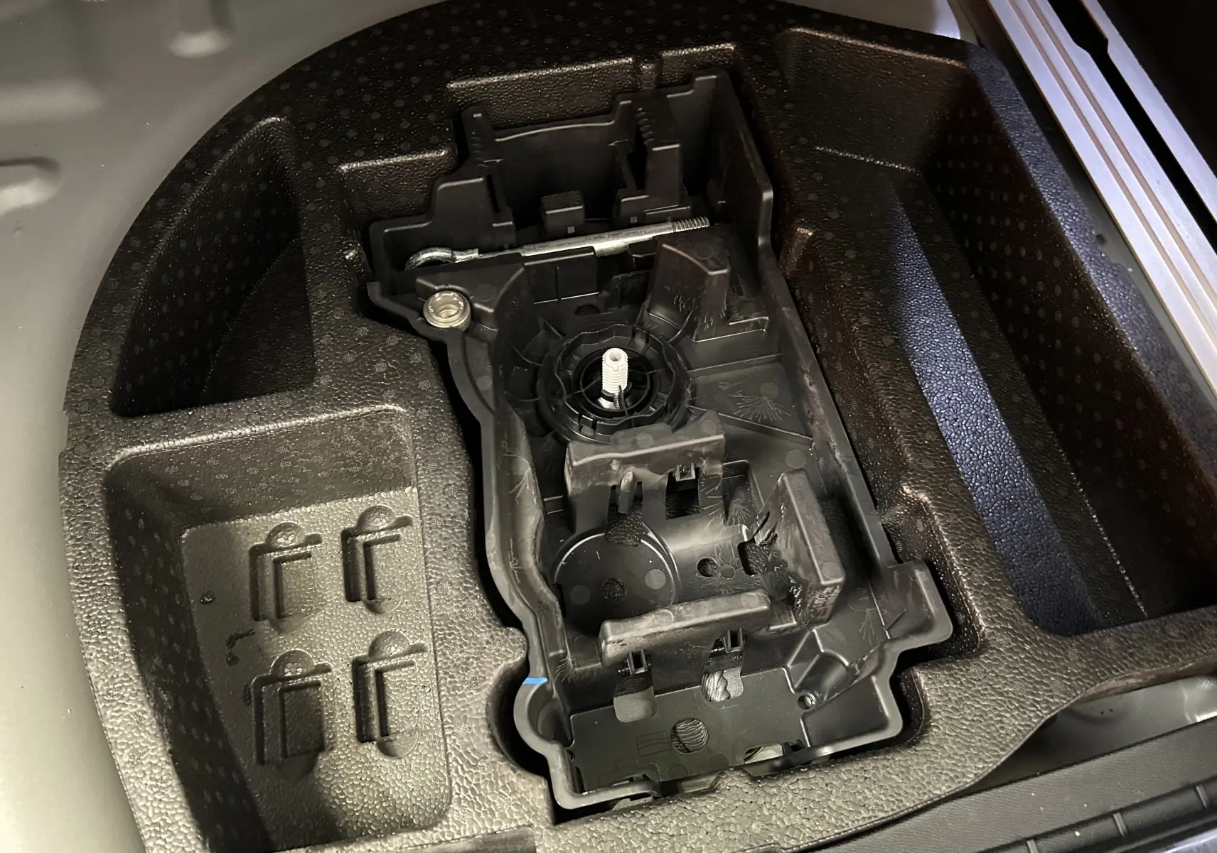 Gros plan sur le rangement en mousse du coffre d'une Peugeot 508 SW gris artense, montrant un support d'outils intégré.