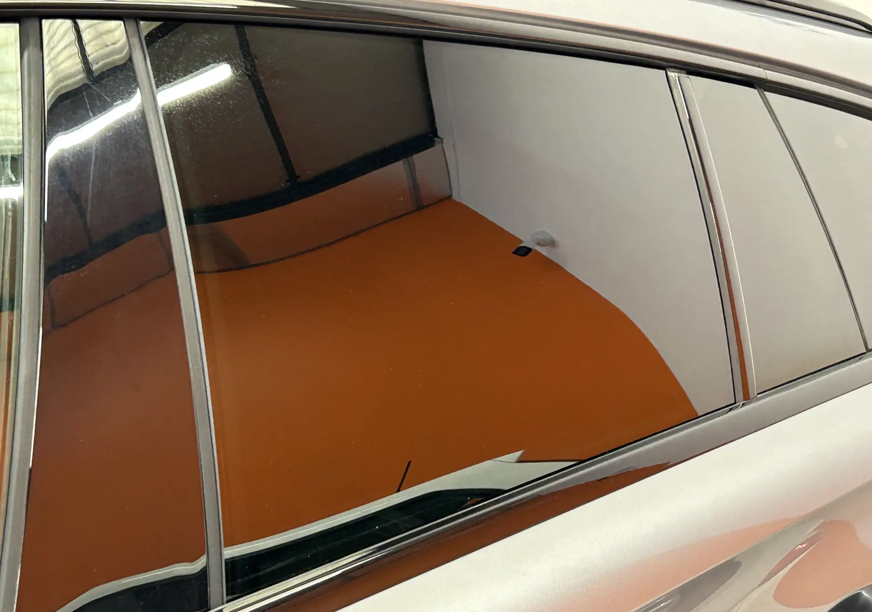 Reflet sur la vitre arrière côté gauche d'une Peugeot 508 SW gris artense, montrant la carrosserie lisse et brillante.