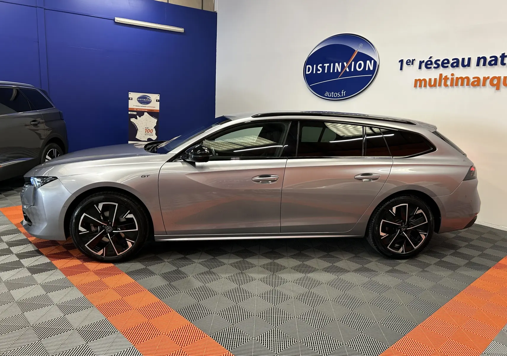 Peugeot 508 SW BlueHDi 130 GT gris artense vue de profil côté gauche en intérieur showroom avec jantes noires.