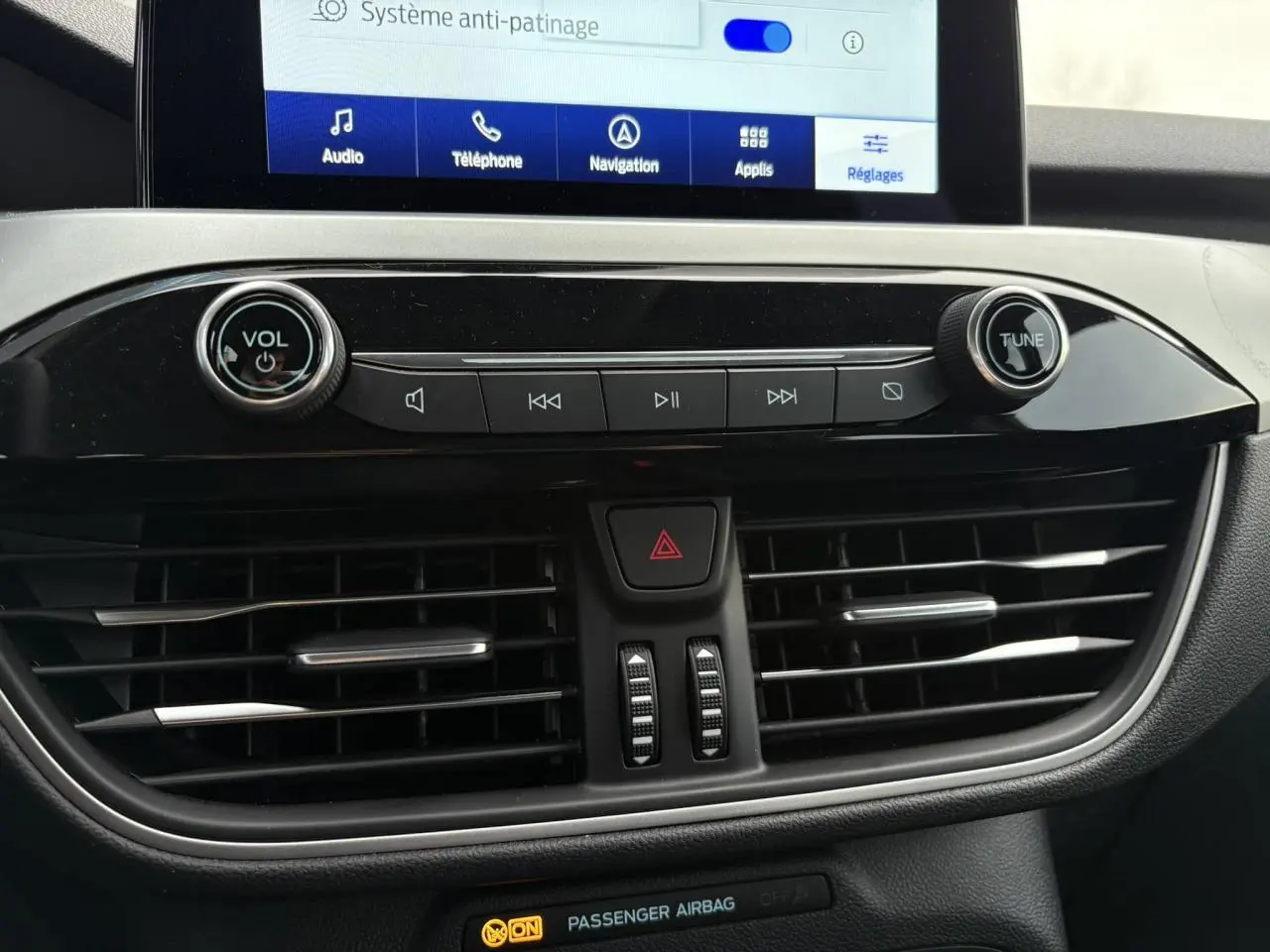 Vue rapprochée de la console centrale du Ford Kuga 2024, avec écran tactile et commandes audio noires brillantes.