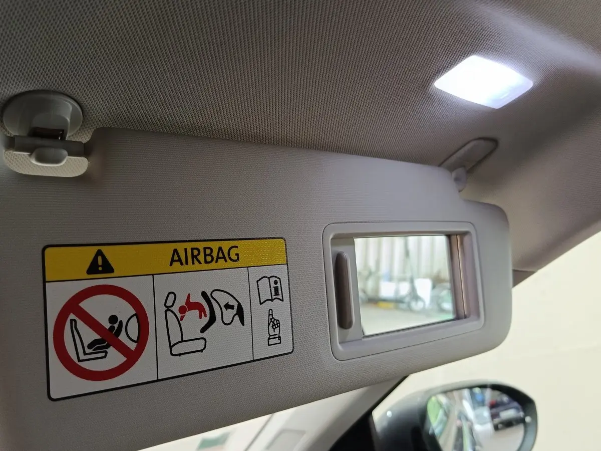 Détail du pare-soleil côté conducteur avec miroir et étiquette d'avertissement airbag dans un Volkswagen Taigo gris foncé.