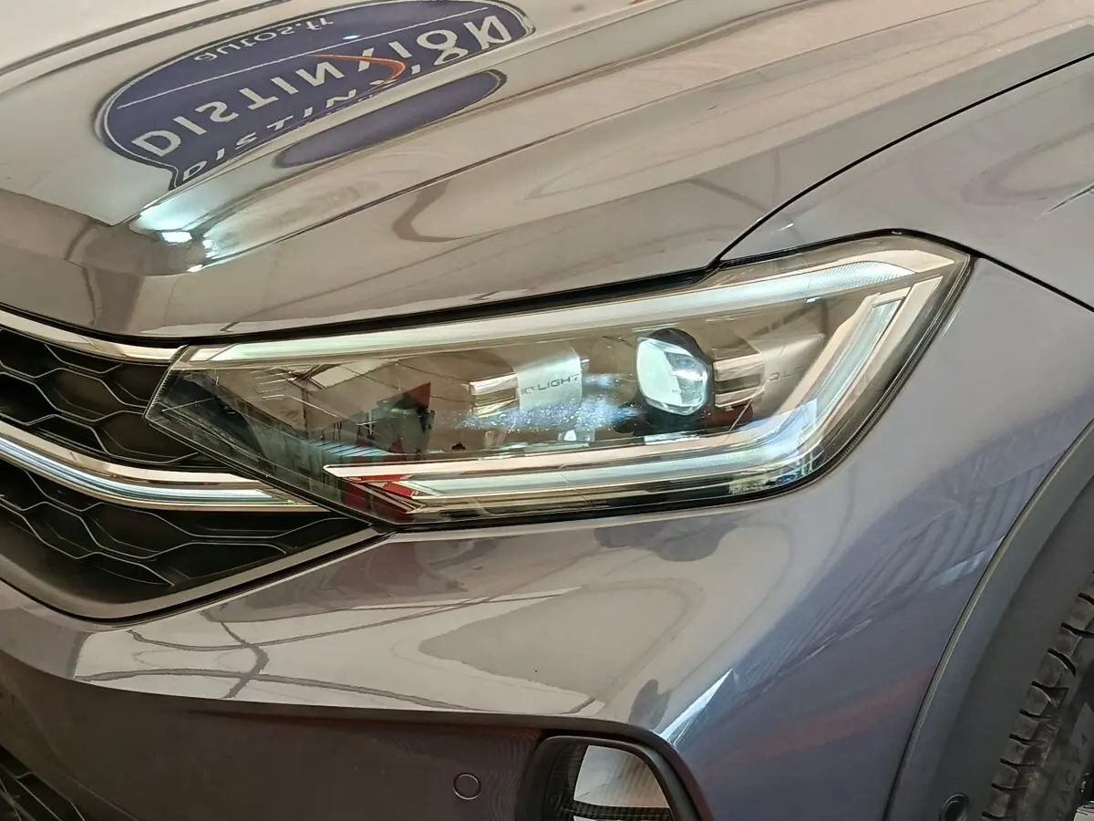 Gros plan sur le phare avant droit gris foncé du Volkswagen Taigo 1.5 TSI 150 DSG Style 2023 avec calandre noire.