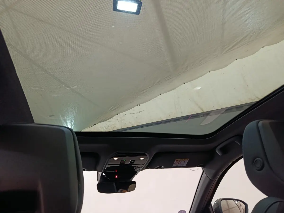 Vue intérieure du toit ouvrant panoramique du Renault Austral gris clair, avec partie des sièges avant visibles.