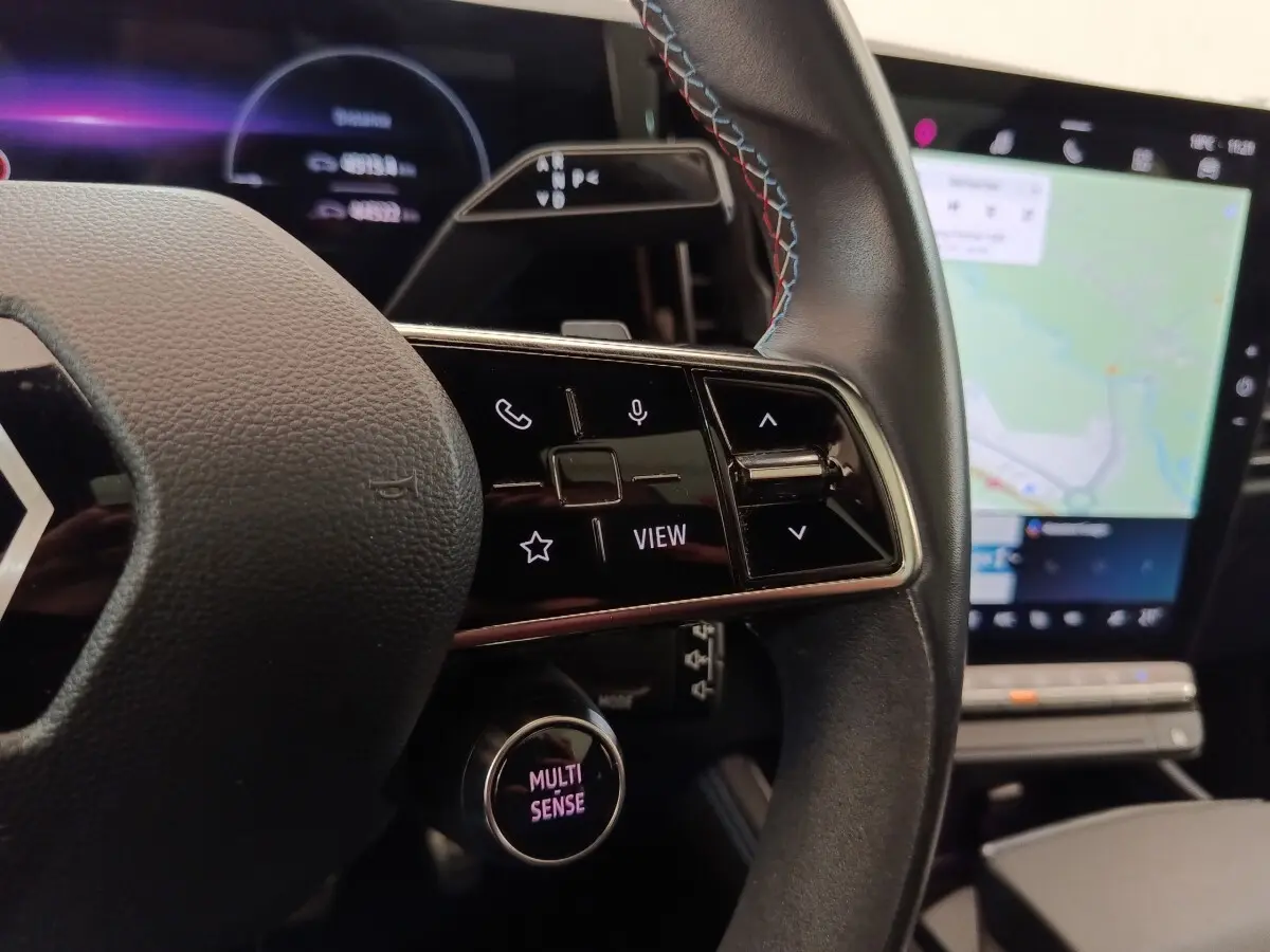 Gros plan sur le volant cuir et suede avec commandes multifonctions, écran tactile et tableau de bord numérique du Renault Austral gris clair.