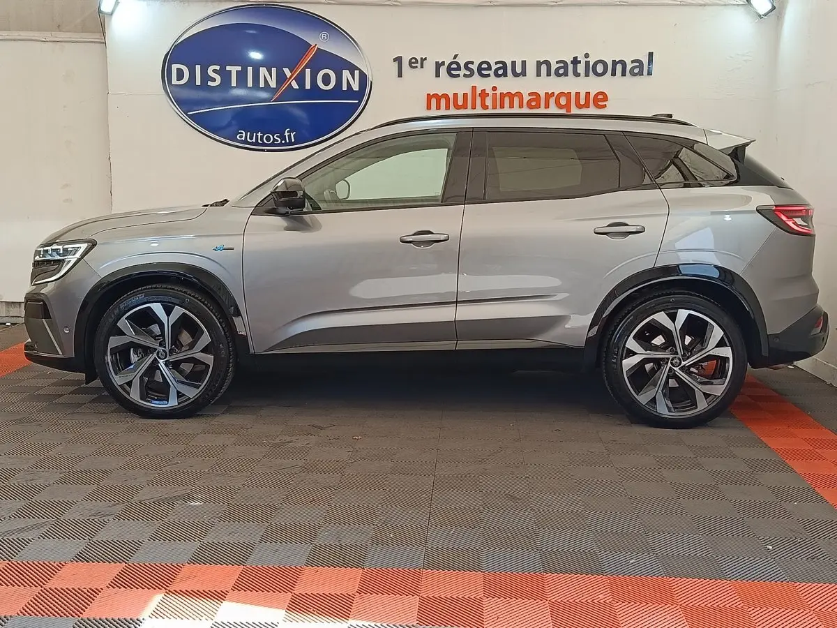 Profil droit du Renault Austral gris clair 2024 avec jantes alliage et toit noir contrasté en intérieur showroom.