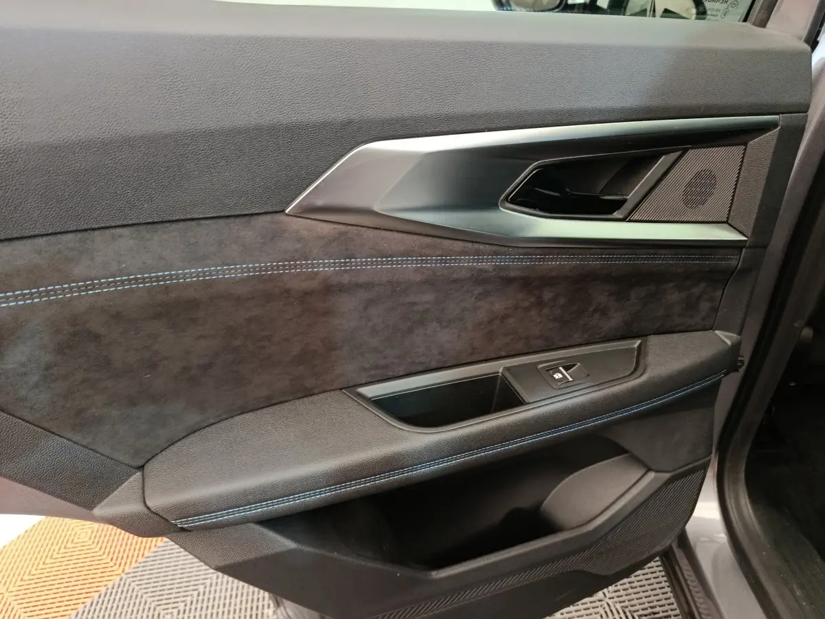 Détail de la porte avant droite du Renault Austral gris clair, avec surpiqûres bleues et insert aluminium.