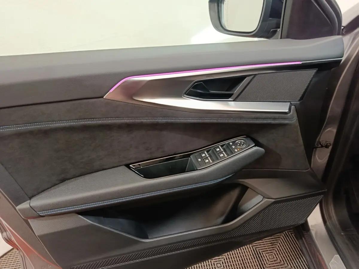 Vue intérieure du panneau de porte avant droit du Renault Austral gris clair avec éclairage d'ambiance violet et commandes de vitres.