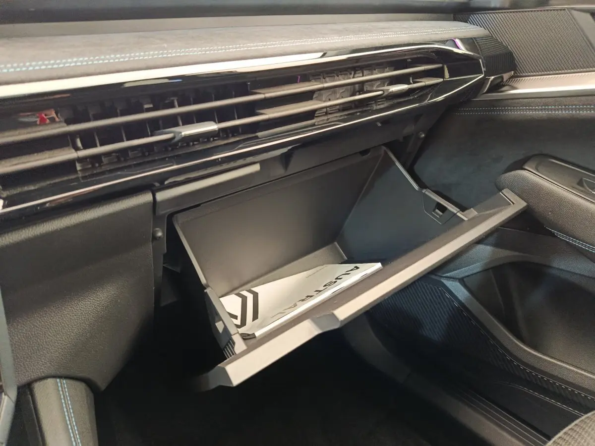 Vue intérieure côté passager du coffre à gants ouvert dans un Renault Austral gris clair, avec livret visible à l'intérieur.