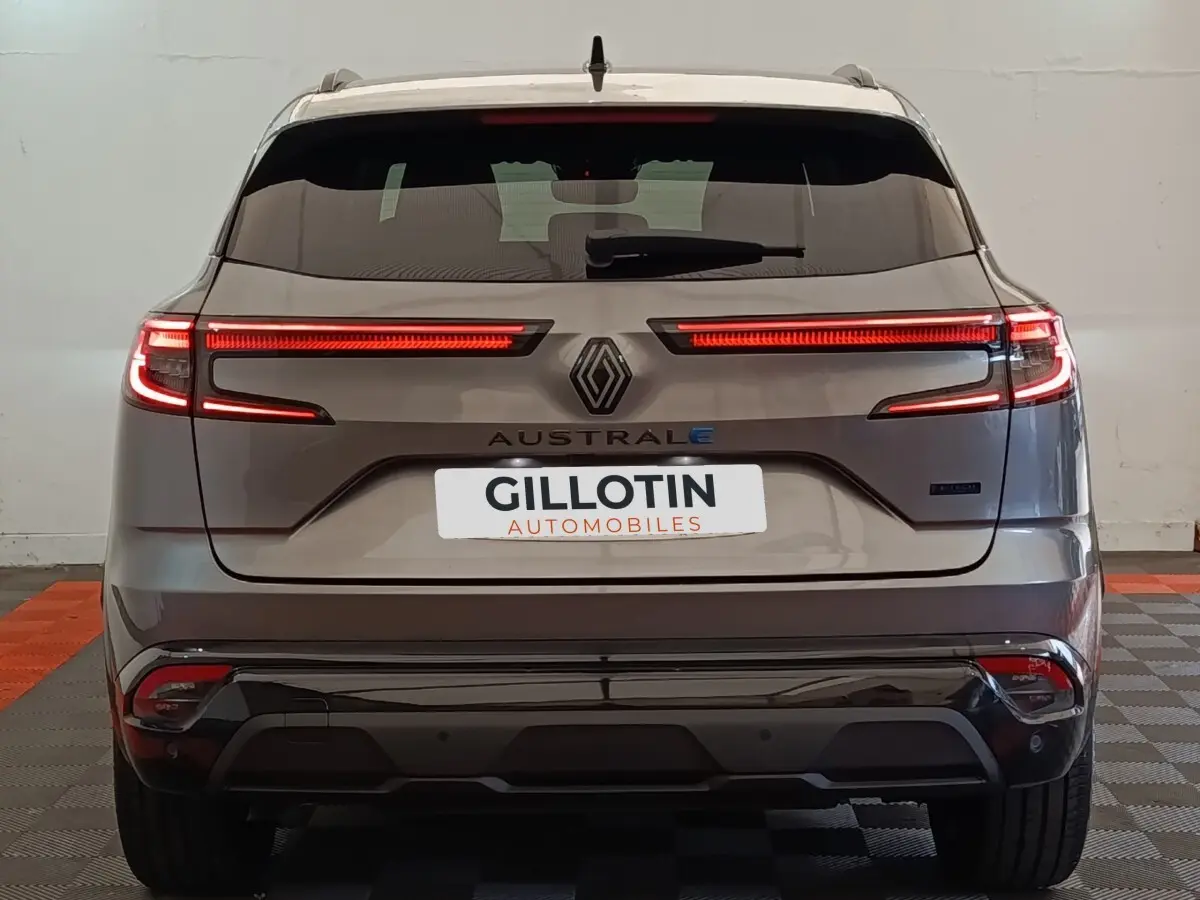 Vue arrière du Renault Austral gris clair 2024 avec feux LED allumés et logo central visible.