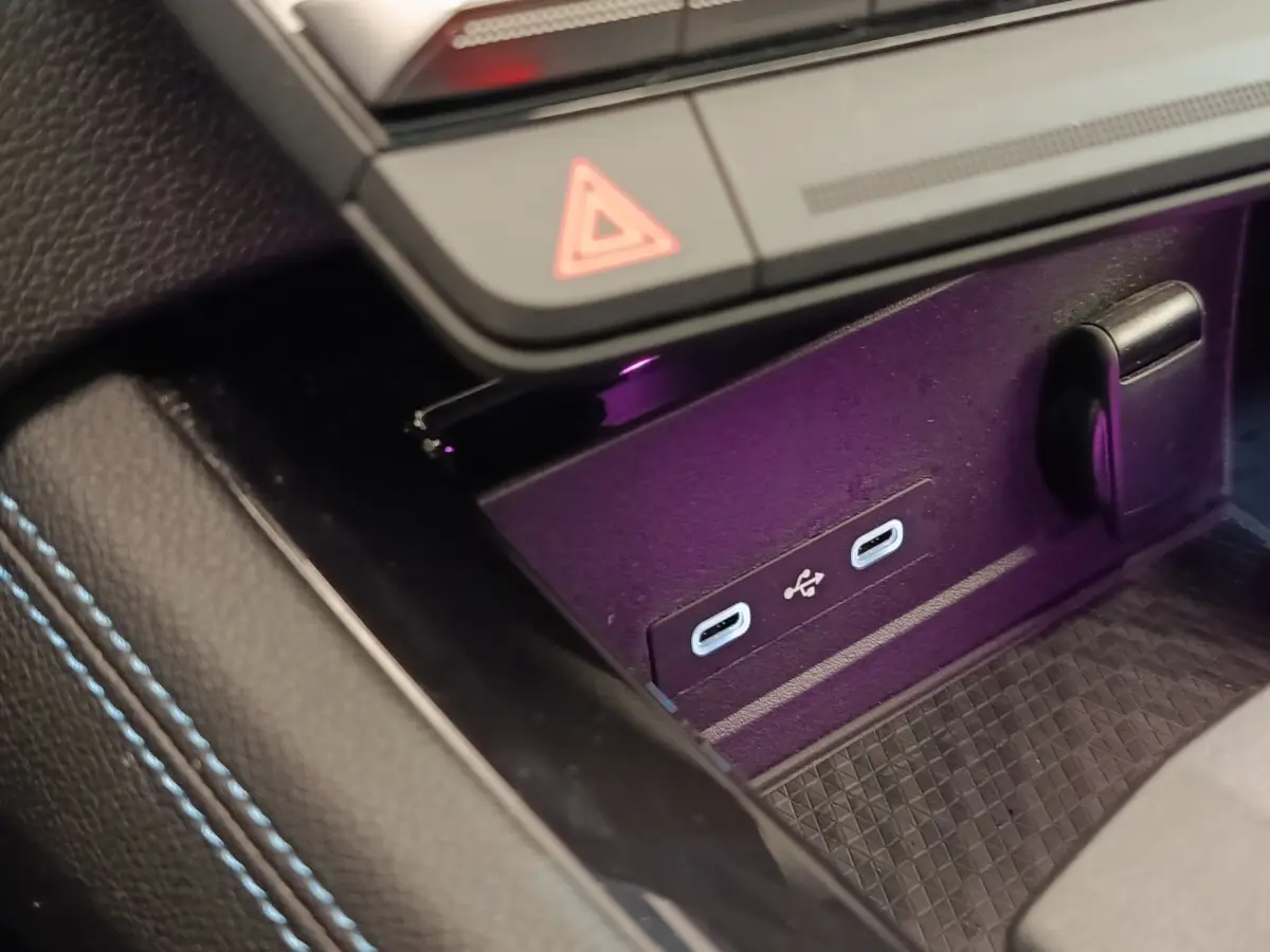 Gros plan sur la console centrale du Renault Austral gris clair, montrant deux ports USB-C et un bouton de signalisation.