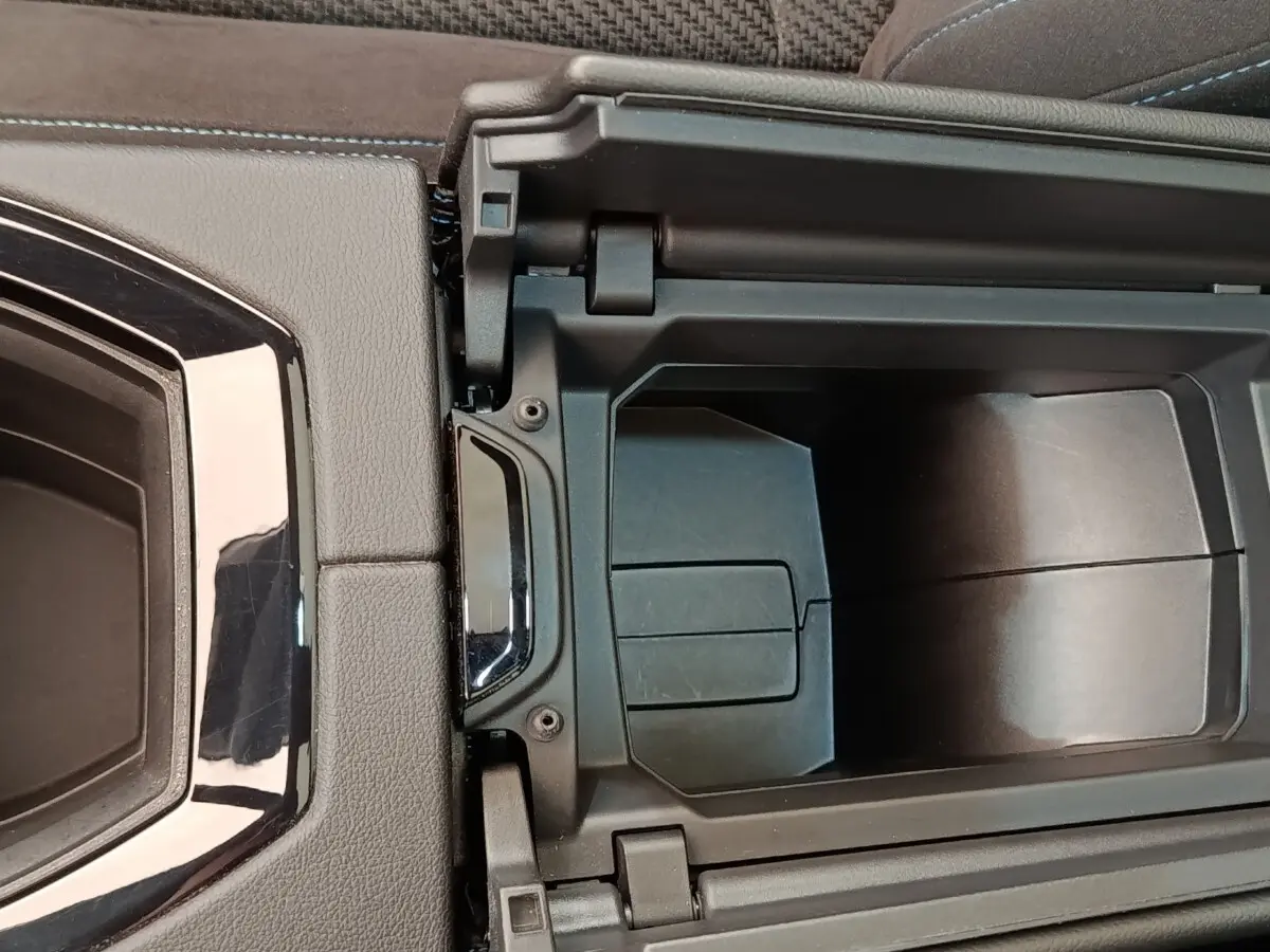 Vue rapprochée de la console centrale ouverte du Renault Austral Iconic Esprit Alpine gris clair, montrant le rangement intérieur.