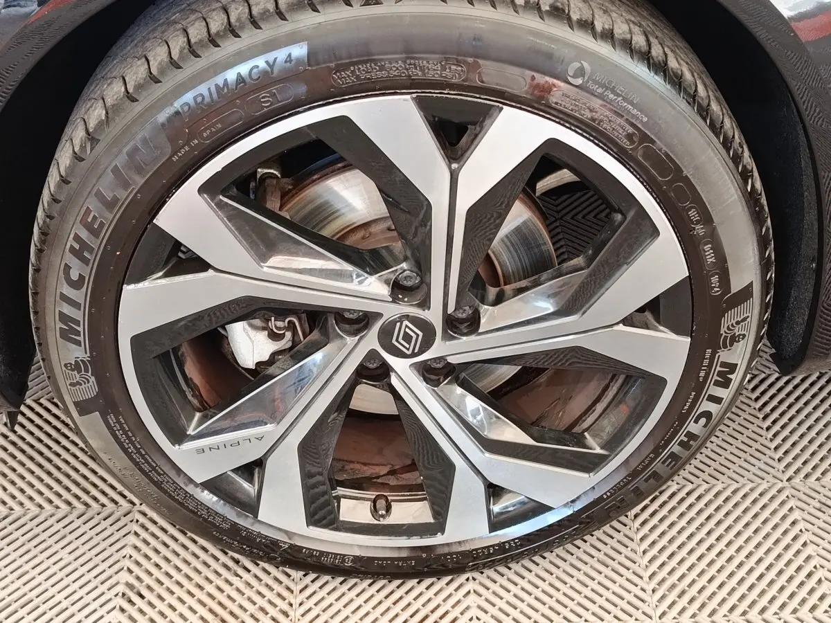 Gros plan sur la jante alu bicolore avec logo Alpine et pneu Michelin Primacy 4 sur Renault Austral gris clair.