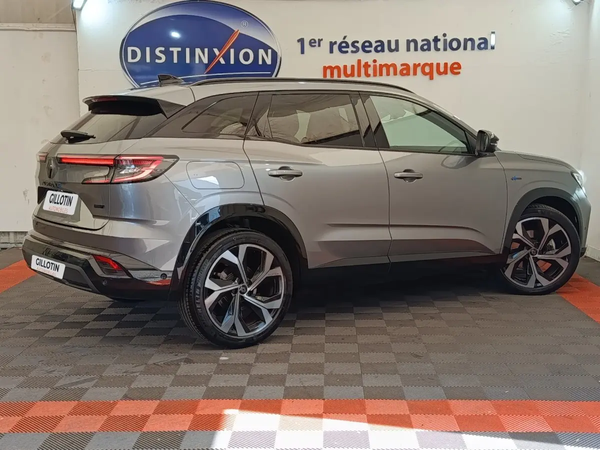 Vue latérale droite du Renault Austral gris clair avec jantes noires et détails Alpine E-Tech, en intérieur showroom.