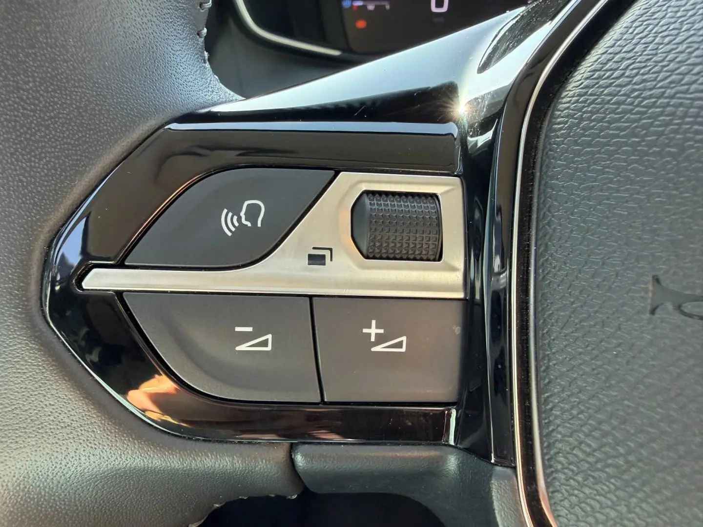 Gros plan sur les commandes audio au volant noir brillant de la Peugeot 208 1.2 100ch S&S Allure 2025.
