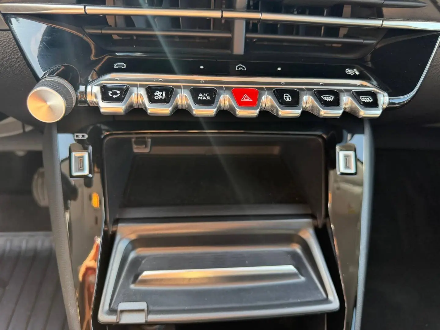 Gros plan sur la console centrale de la Peugeot 208 1.2 100ch Allure, montrant les commandes clim et rangement ouvert.