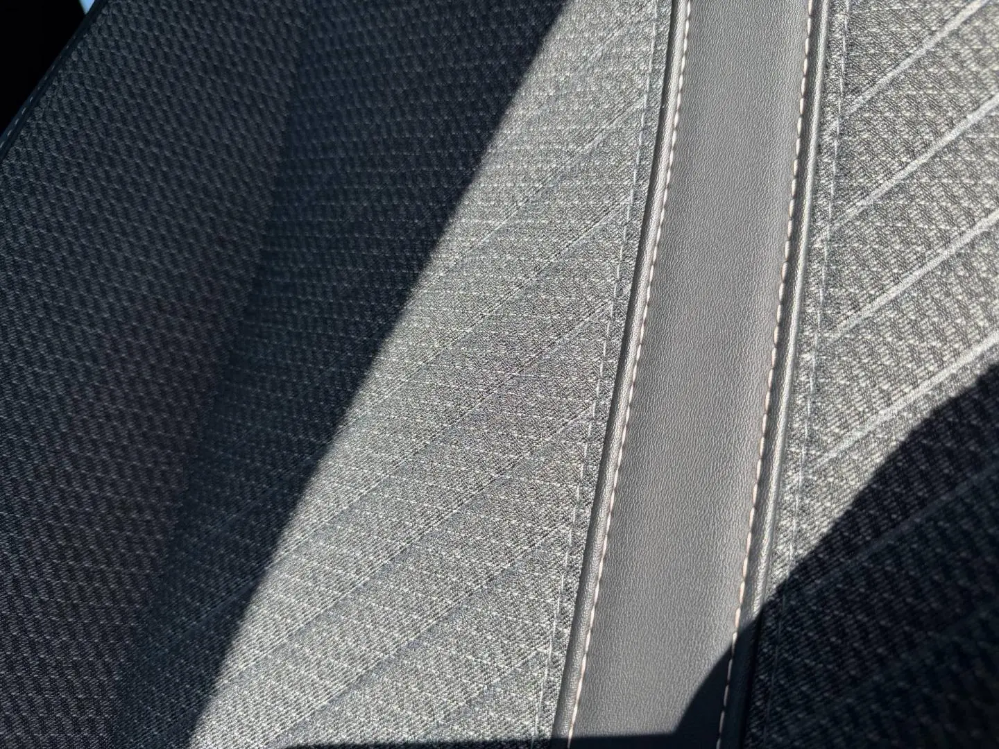 Détail du tissu gris clair Casual Lomsa avec surpiqûres sur la banquette avant du Peugeot 208 1.2 100ch Allure 2025.