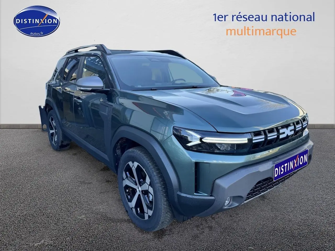 Vue 3/4 avant d'un Dacia Duster 2025 vert cèdre avec jantes alu et barres de toit visibles.