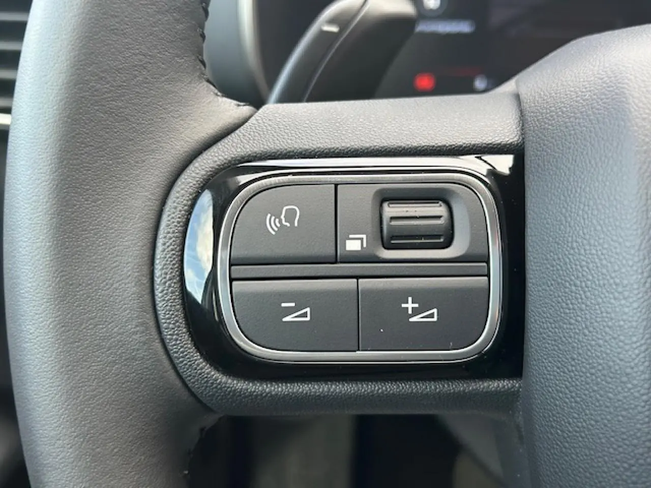 Gros plan sur les commandes noires du volant en cuir du Citroën C5 Aircross 2025, version diesel bleu Eclipse Metal.