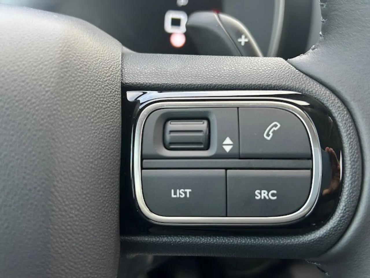Gros plan sur les commandes gauche du volant noir du Citroën C5 Aircross 2025, boutons pour appels et listes.