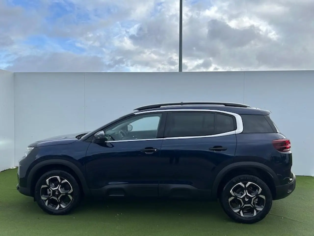 Profil côté gauche d'un Citroën C5 Aircross bleu Eclipse métallisé avec jantes alliage 18'' bi-ton et vitres surteintées.
