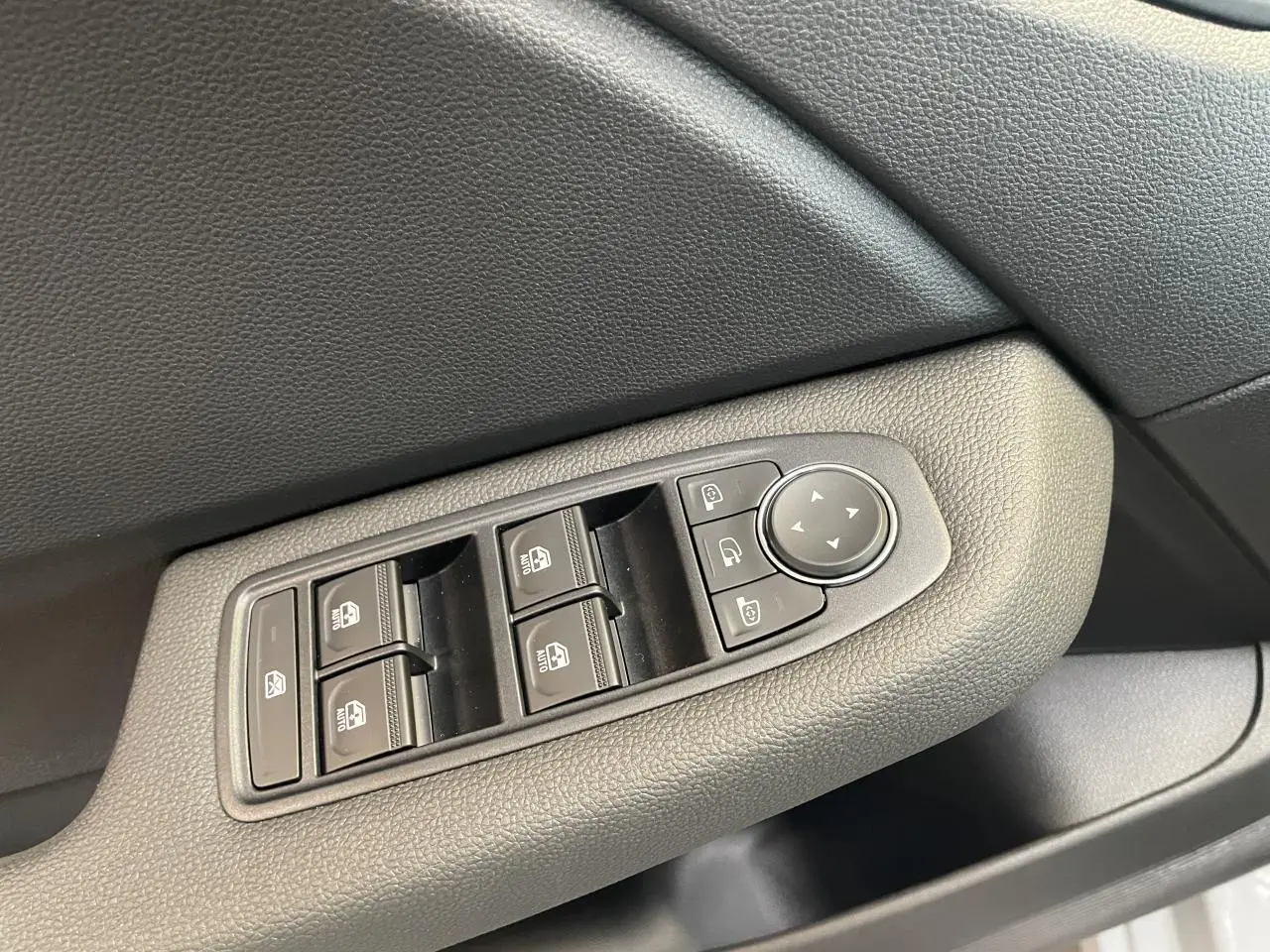 Gros plan sur les commandes de lève-vitres et rétroviseurs côté conducteur d'une Renault Clio 1.5 Blue dCi gris Rafale.