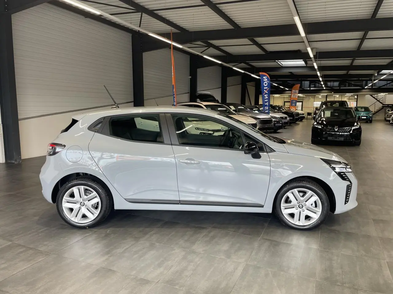 Profil droit d'une Renault Clio 1.5 Blue dCi 2025 gris Rafale, avec jantes alliage et poignées couleur carrosserie.