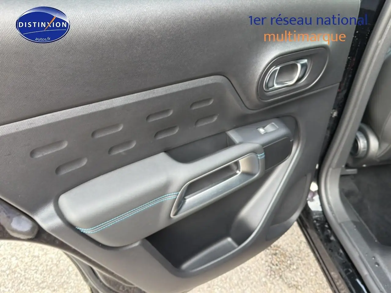 Gros plan sur la porte avant gauche noire perla nera du Citroën C5 Aircross 2025 avec surpiqûres bleues et poignée intégrée.