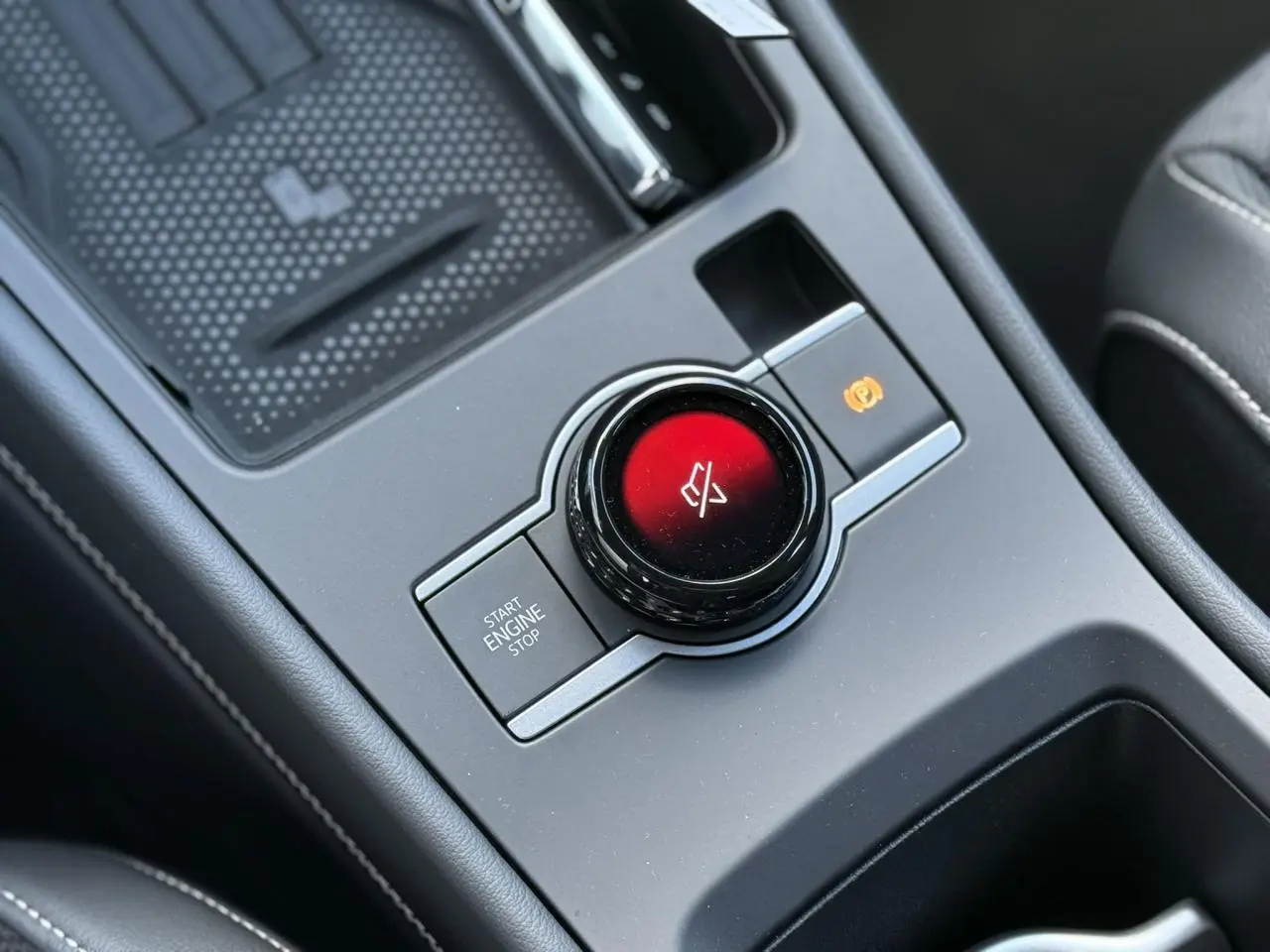 Gros plan sur la console centrale noire du Volkswagen T-Roc 2026, avec bouton start/stop et commande électronique de frein à main.
