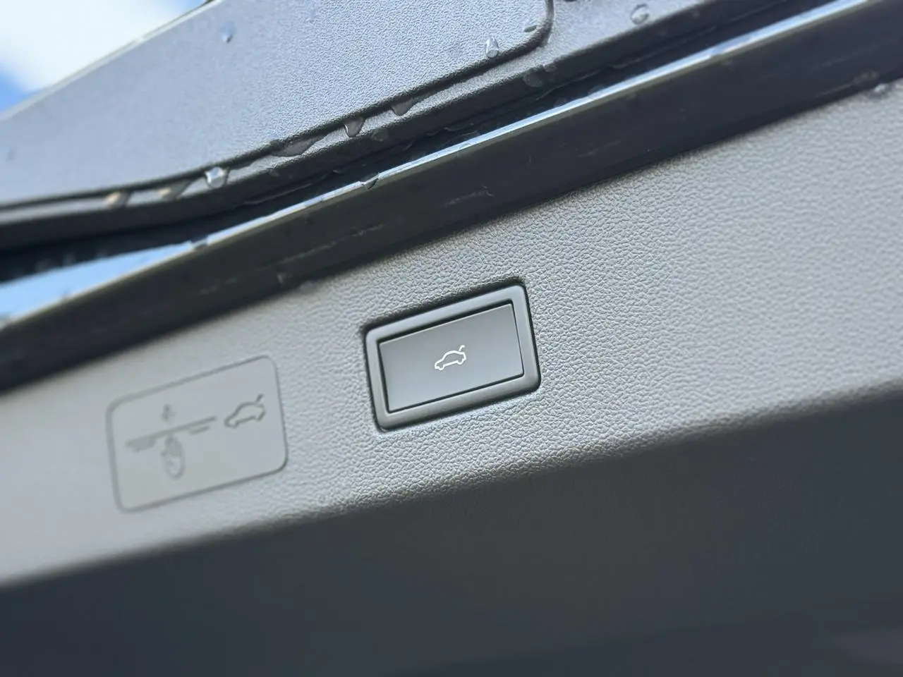 Détail du bouton d'ouverture électrique du hayon sur un Volkswagen T-Roc noir Ébène 2026.