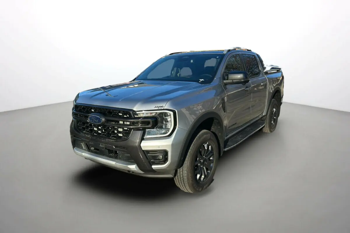 Ford Ranger 2.0 Wildtrak Plus gris iconic en 3/4 avant droit avec barres de toit et jantes alu noires.