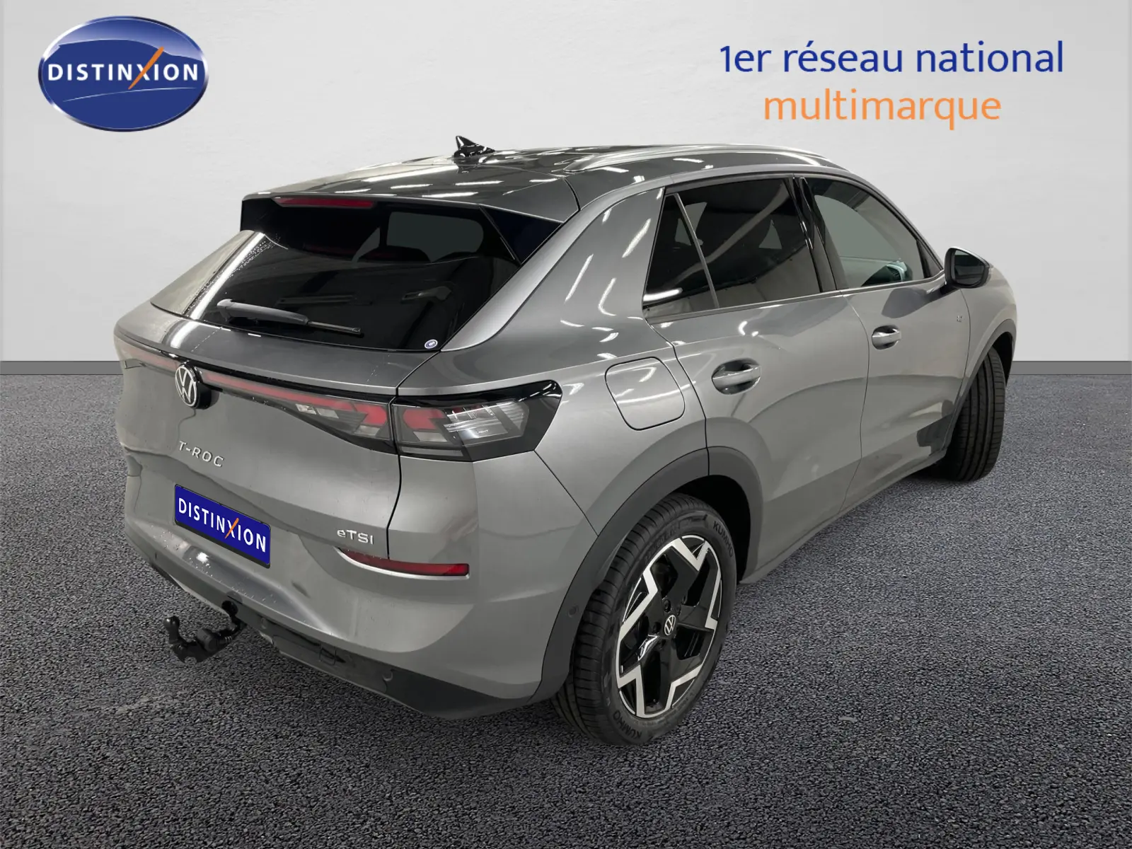 Vue 3/4 arrière droite du Volkswagen T-Roc gris Loup avec attelage escamotable et vitres arrière surteintées.