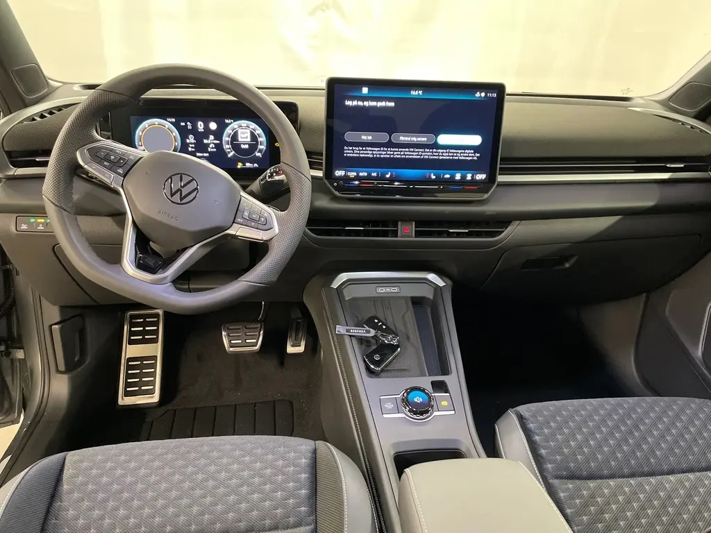 Vue intérieure avant du Volkswagen T-Roc 2026, tableau de bord noir avec volant sport multifonction et écran tactile central.