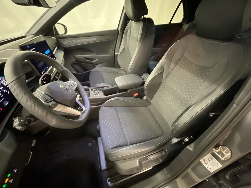 Vue intérieure côté conducteur du Volkswagen T-Roc gris Loup 2026, sièges sport R-Line et volant multifonction cuir.