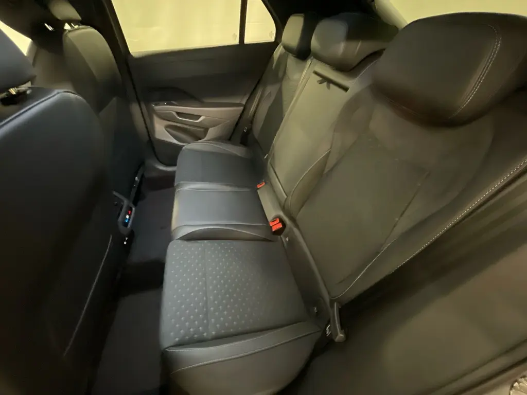 Vue intérieure arrière droite des sièges tissu noirs du Volkswagen T-Roc 2026 avec accoudoir central et ceintures rouges.