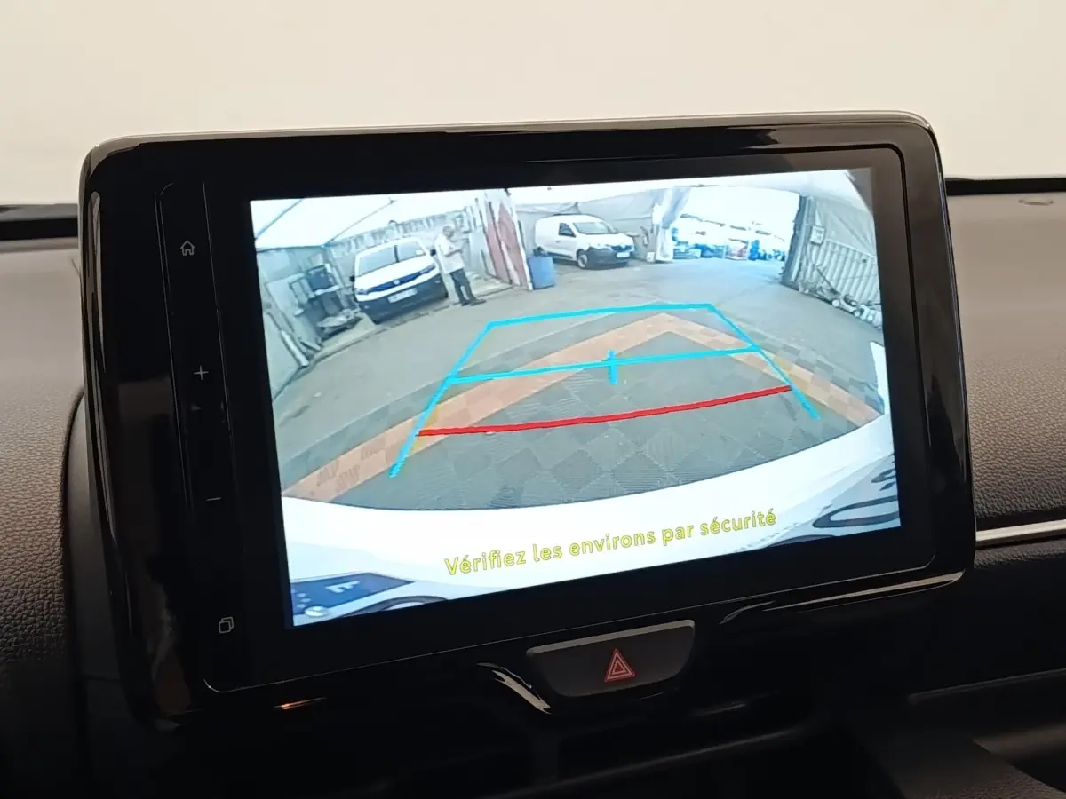 Écran tactile intérieur montrant la caméra de recul avec guidage coloré sur Toyota Yaris Hybride blanche.