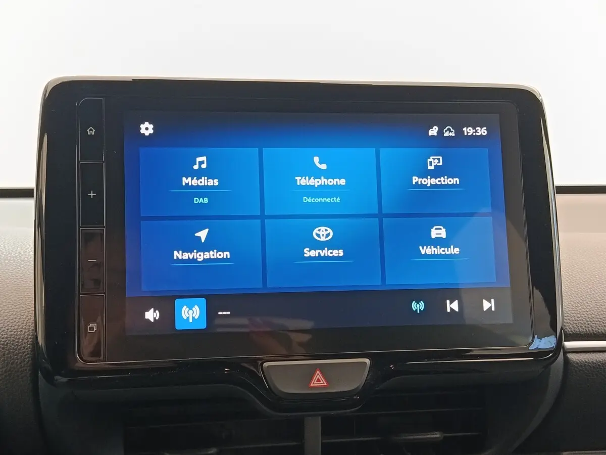 Tableau de bord avec écran tactile 9 pouces affichant menu médias, téléphone, navigation, et services sur Toyota Yaris Hybride blanche.