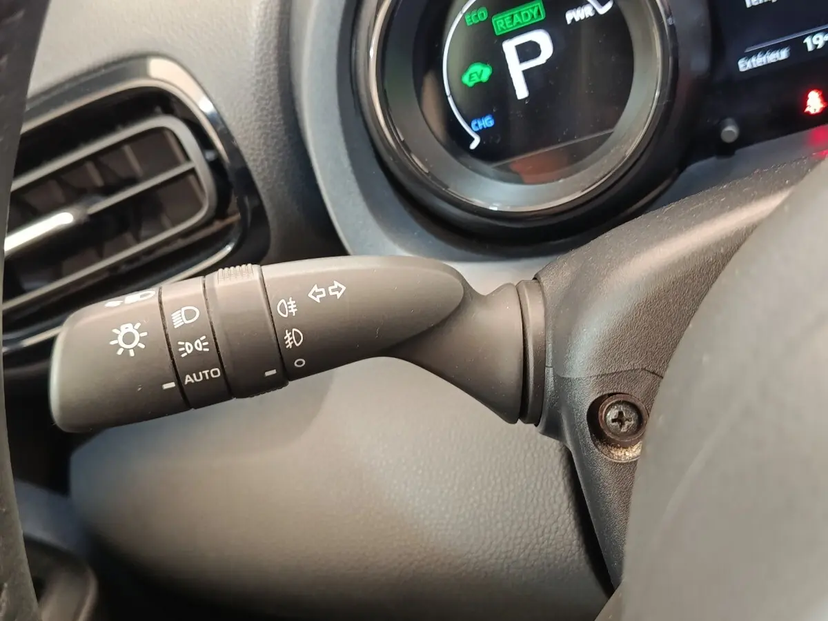 Gros plan sur la commande des phares et clignotants à gauche du volant dans le tableau de bord d’une Toyota Yaris hybride blanche 2022.