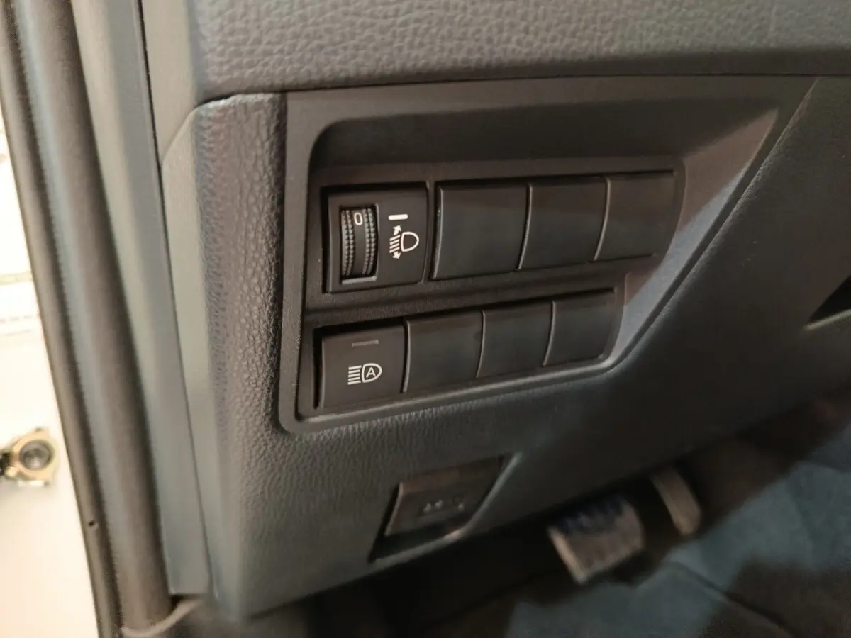 Détail des commandes d’éclairage sur le côté gauche du tableau de bord d’une Toyota Yaris hybride blanche 2022.