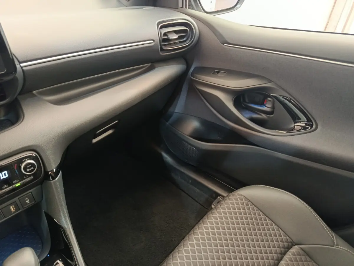 Vue intérieure côté passager avant de la Toyota Yaris Hybride 116h Collection 2022, avec tableau de bord et siège en cuir noir.