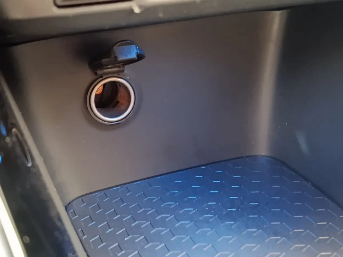 Prise 12V ouverte dans le compartiment de rangement intérieur noir de la Toyota Yaris Hybride 116h Collection 2022.